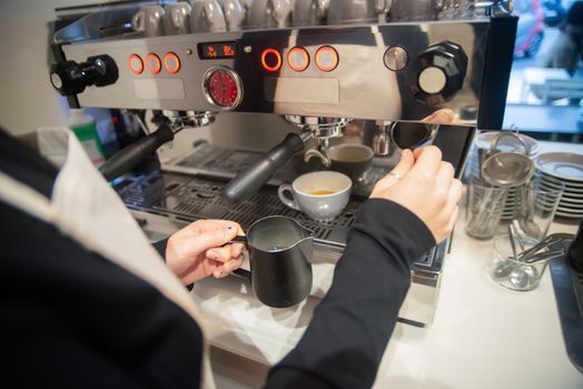 A barista prepares an espresso drink using a modern coffee machine in a café setting.