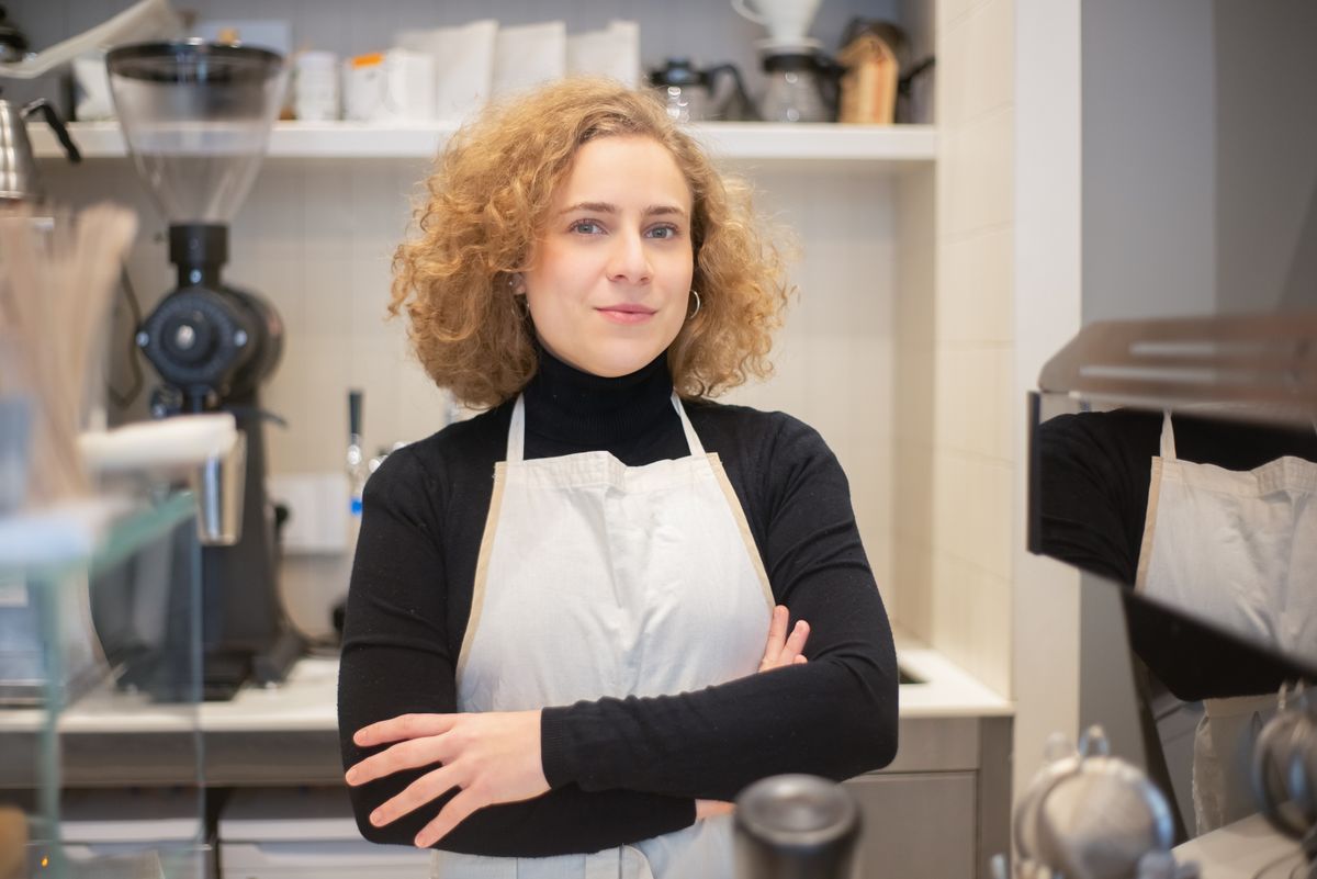 A woman wearing an apron working in a coffee shop