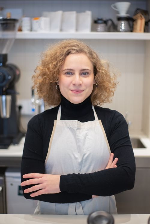 Free A cheerful barista stands confidently with folded arms in a stylish coffee shop. Stock Photo