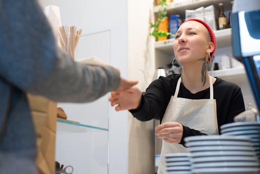Barista with tattoos and red beanie serves a customer in a cozy Portugal café.