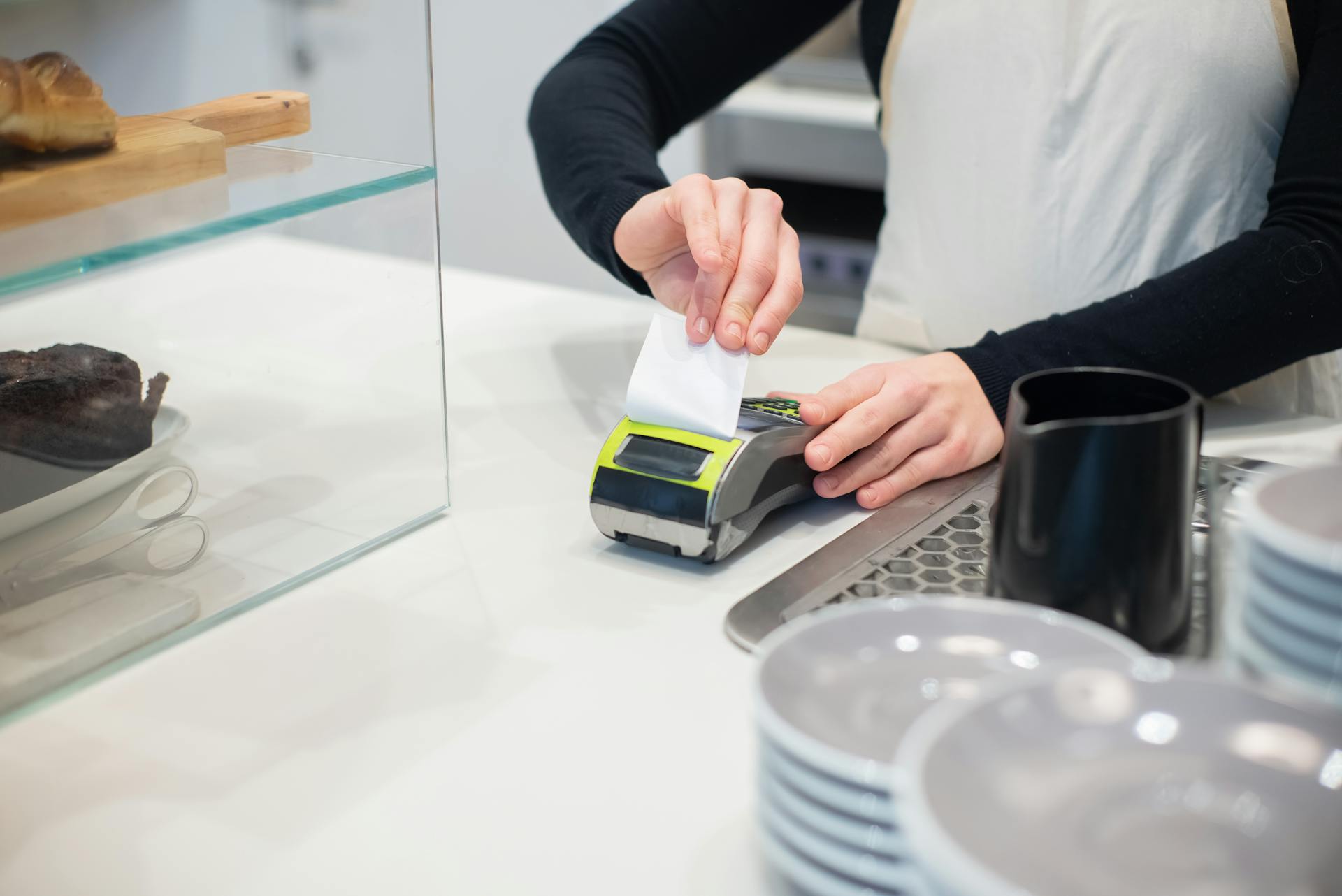 Close-up of a cashless transaction at a modern café counter with hands holding a receipt.