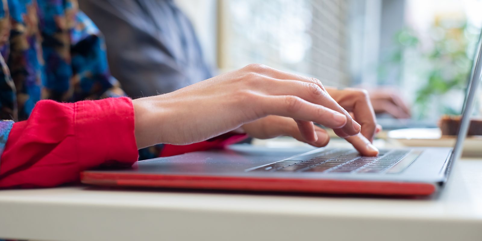 Close-up of hands typing an email on a laptop keyboard