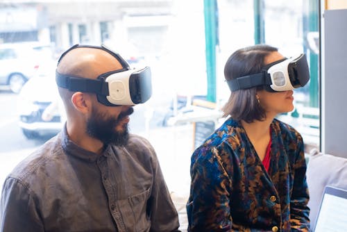 Free Man and Woman Using Virtual Reality Headsets While Sitting Stock Photo