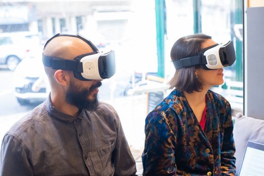 Two adults wearing VR headsets indoors, exploring virtual reality.