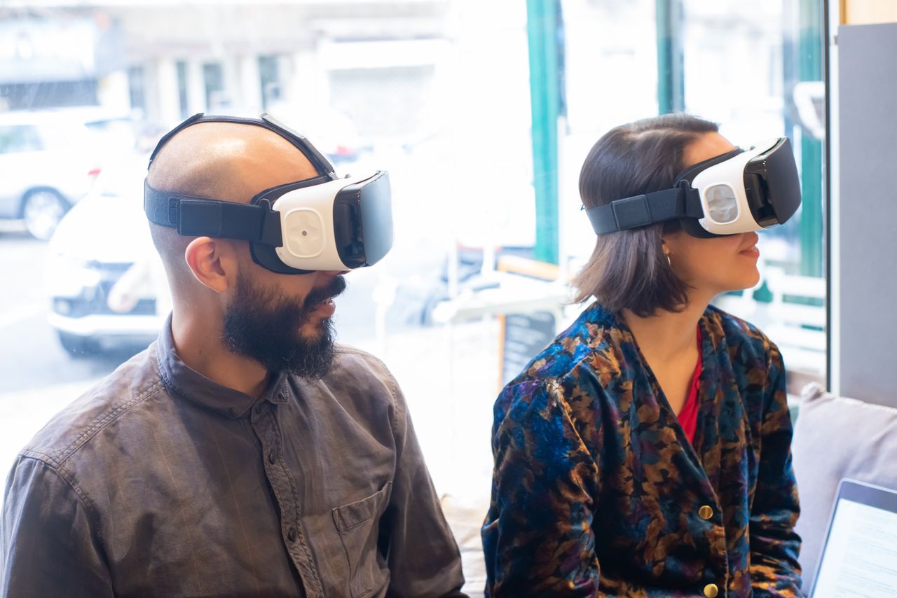 two adults wearing vr headsets indoors exploring virtual reality