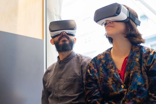 Free A couple wearing VR glasses explores a virtual world indoors, showcasing modern technology and lifestyle. Stock Photo