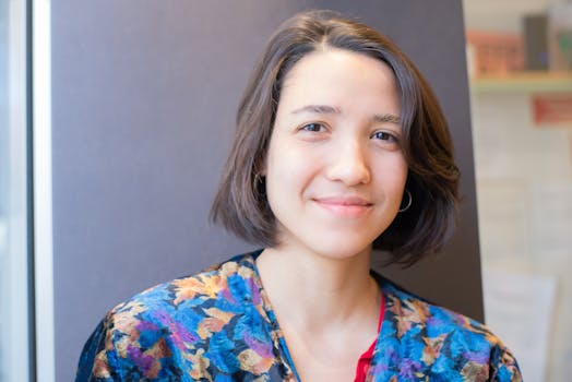 Portrait of a smiling woman with short hair in a colorful floral dress indoors.