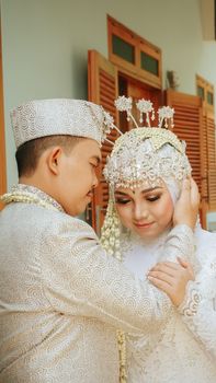 A tender moment between a couple in traditional Indonesian wedding attire. - Fotografer Sidoarjo