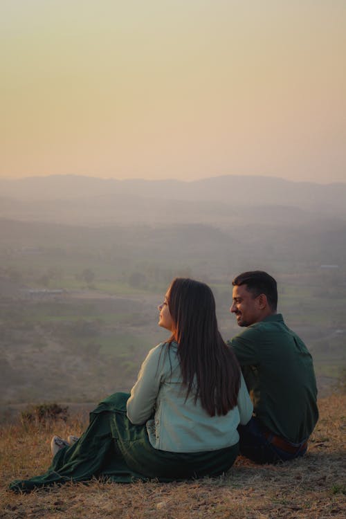 A Couple Sitting on the Brown Grass