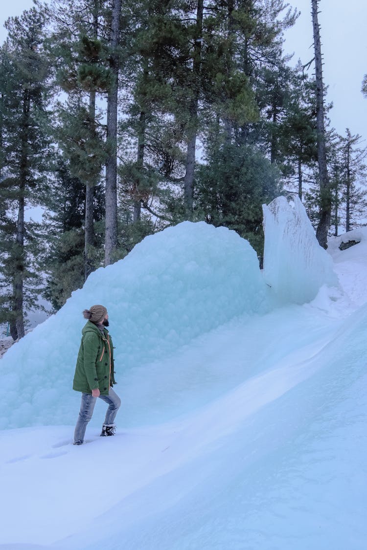 Man Standing In Snow Near Ice Slide