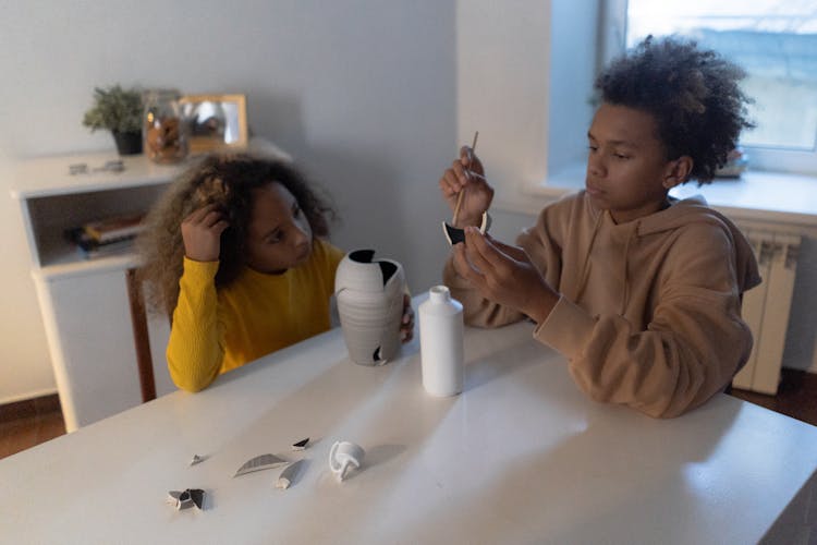 A Brother And Sister Fixing A Broken Vase