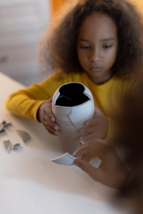 A Young Girl Holding a Broken Vase