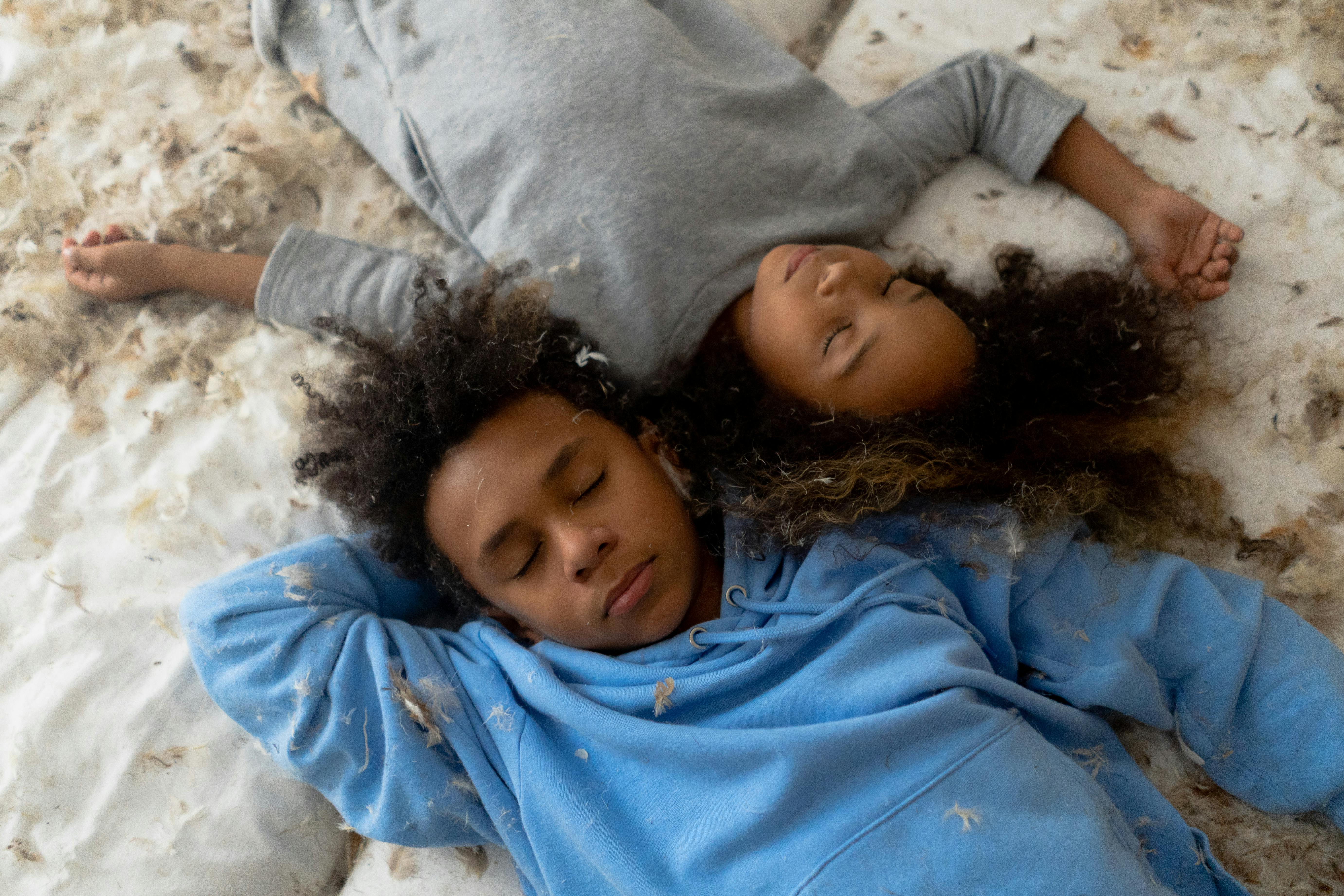 children sleeping on the messy bed