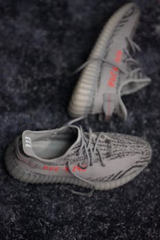 Detailed view of grey athletic shoes on a dark textured floor, showcasing modern footwear design.