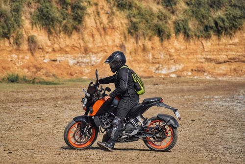 Free Motorcyclist riding an orange motorcycle in rocky outdoor terrain, Kankapura, India. Stock Photo