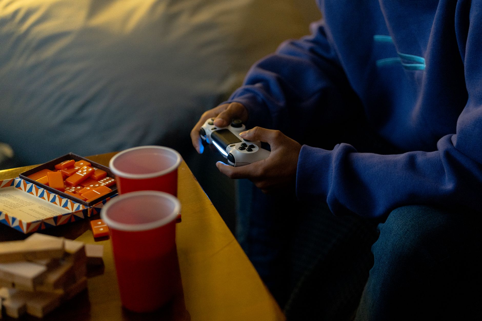 Person enjoying a gaming session with console and snacks indoors.
