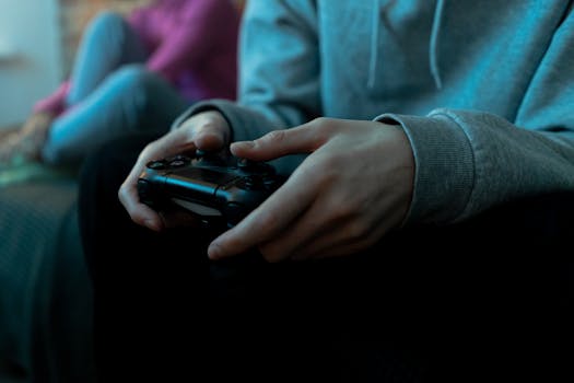 Close-up of hands holding a video game controller, focused in an indoor setting.