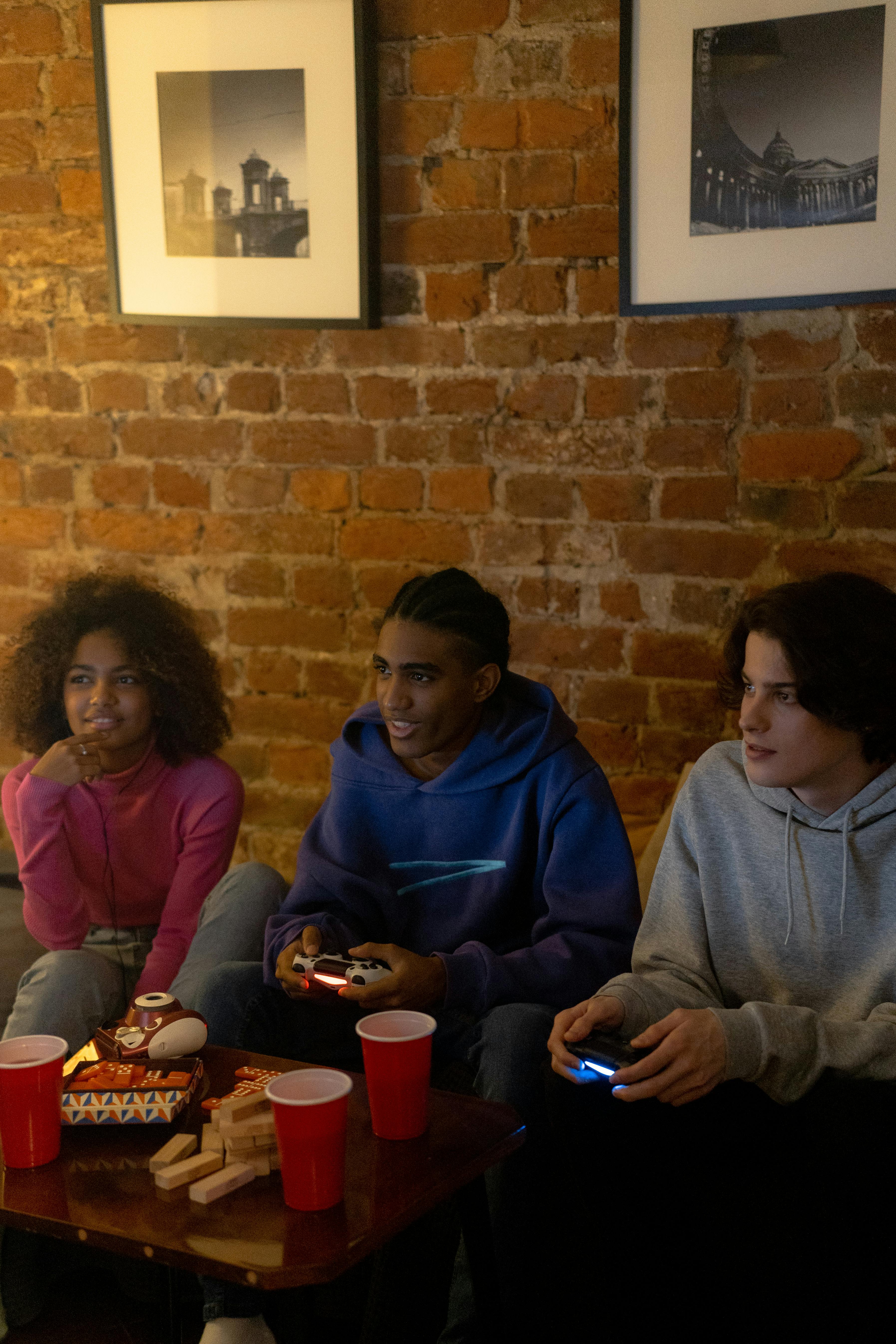 Three teens have fun playing video games together, bonding over a shared hobby indoors.