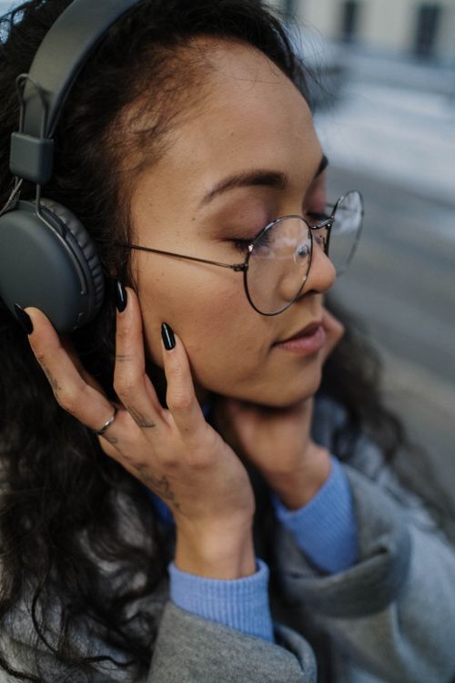 Free Young woman with glasses, eyes closed, wearing headphones, enjoying music. Stock Photo