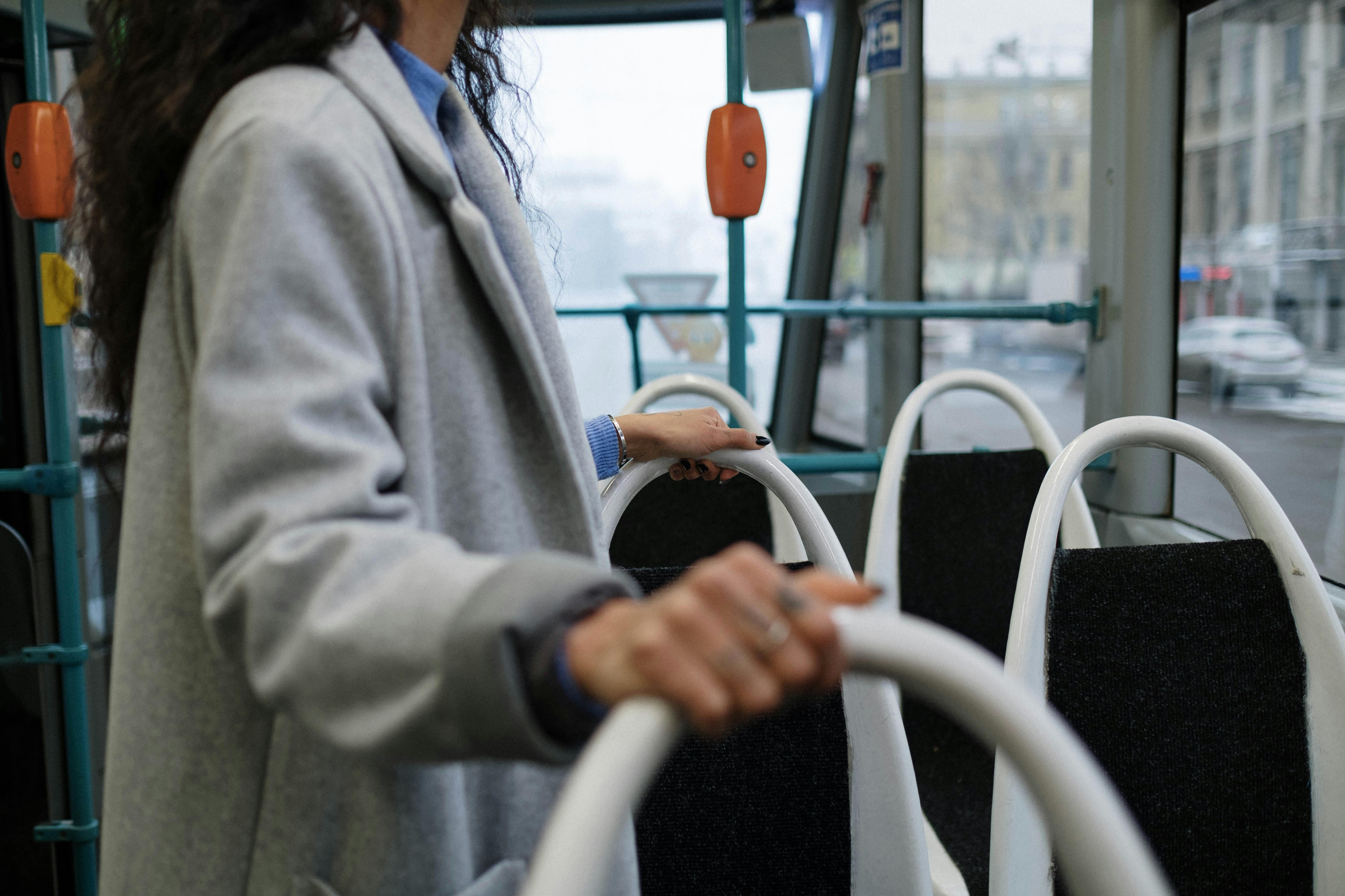 a person in gray coat standing inside a bus