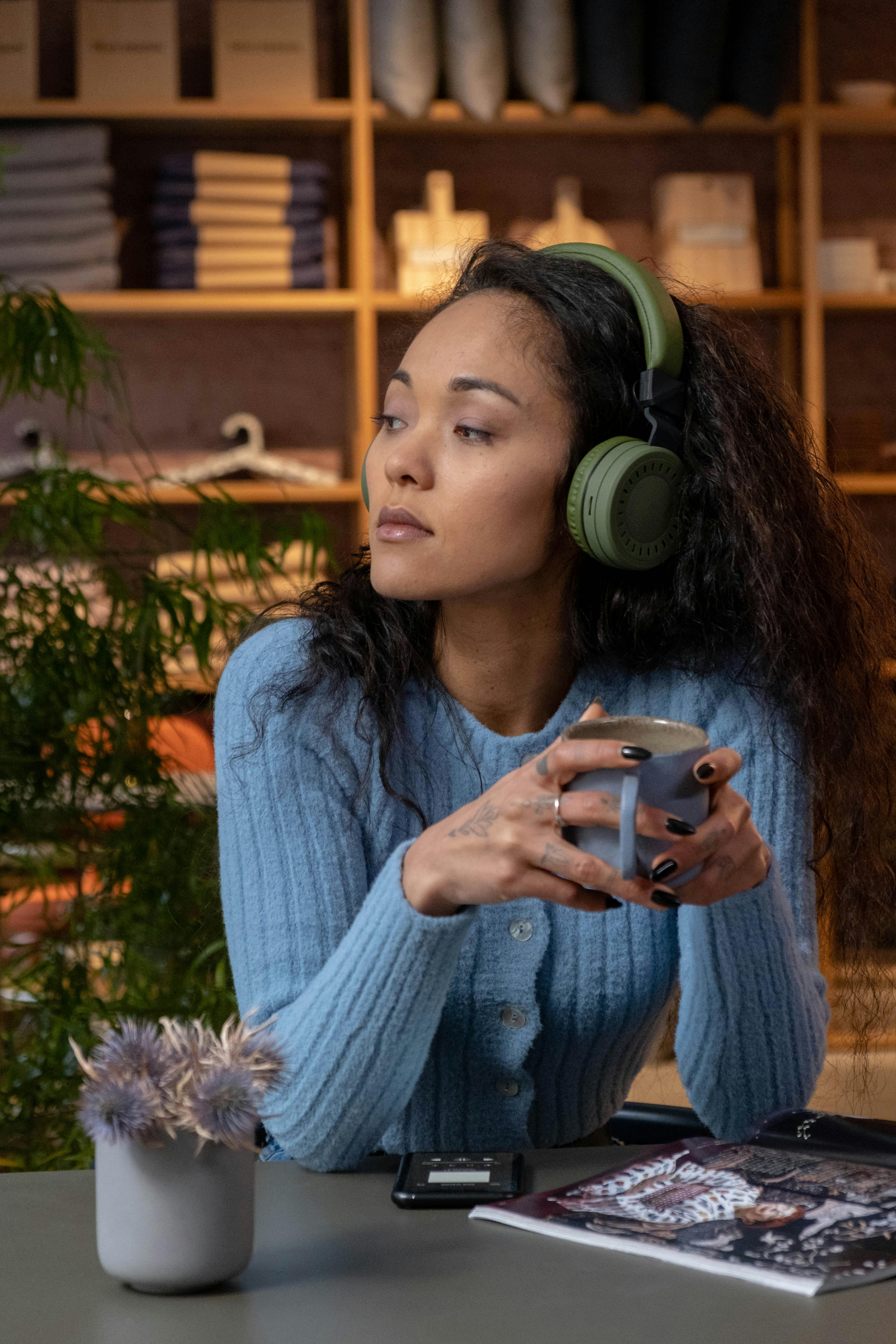 a woman in a blue sweater sitting while holding a blue mug