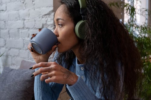 Free Close-Up Shot of a Woman Drinking Beverage While Listening to Music Stock Photo