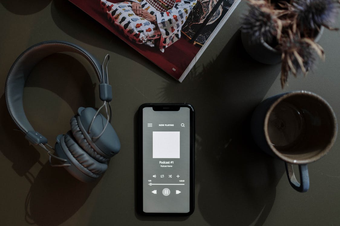 Free Overhead Shot of a Cellphone between a Mug and Headphones Stock Photo