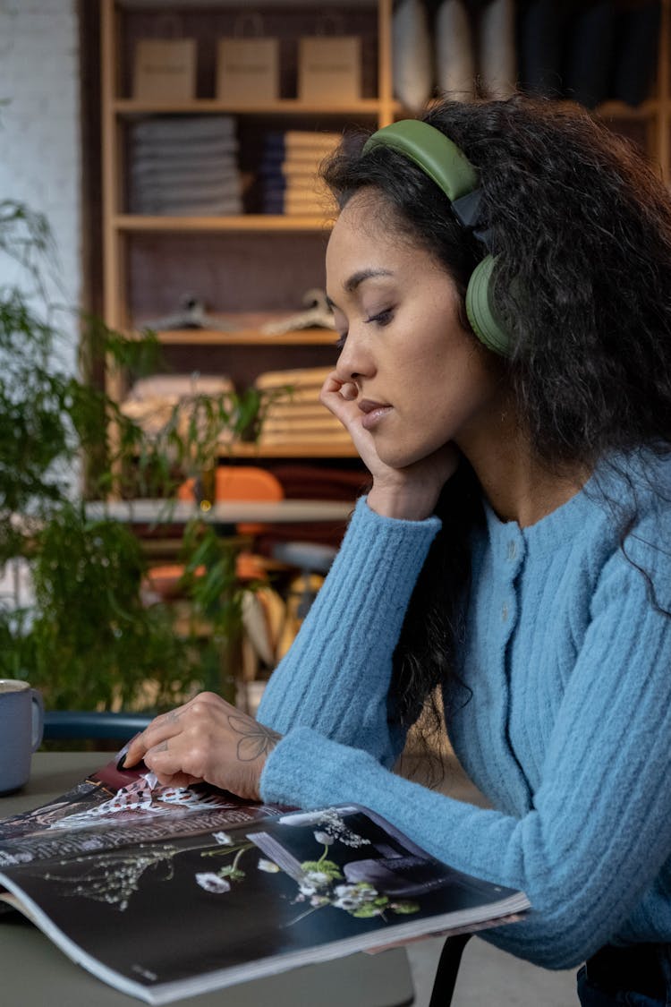 Close-Up Shot Of A Woman In Blue Sweater Reading A Magazine