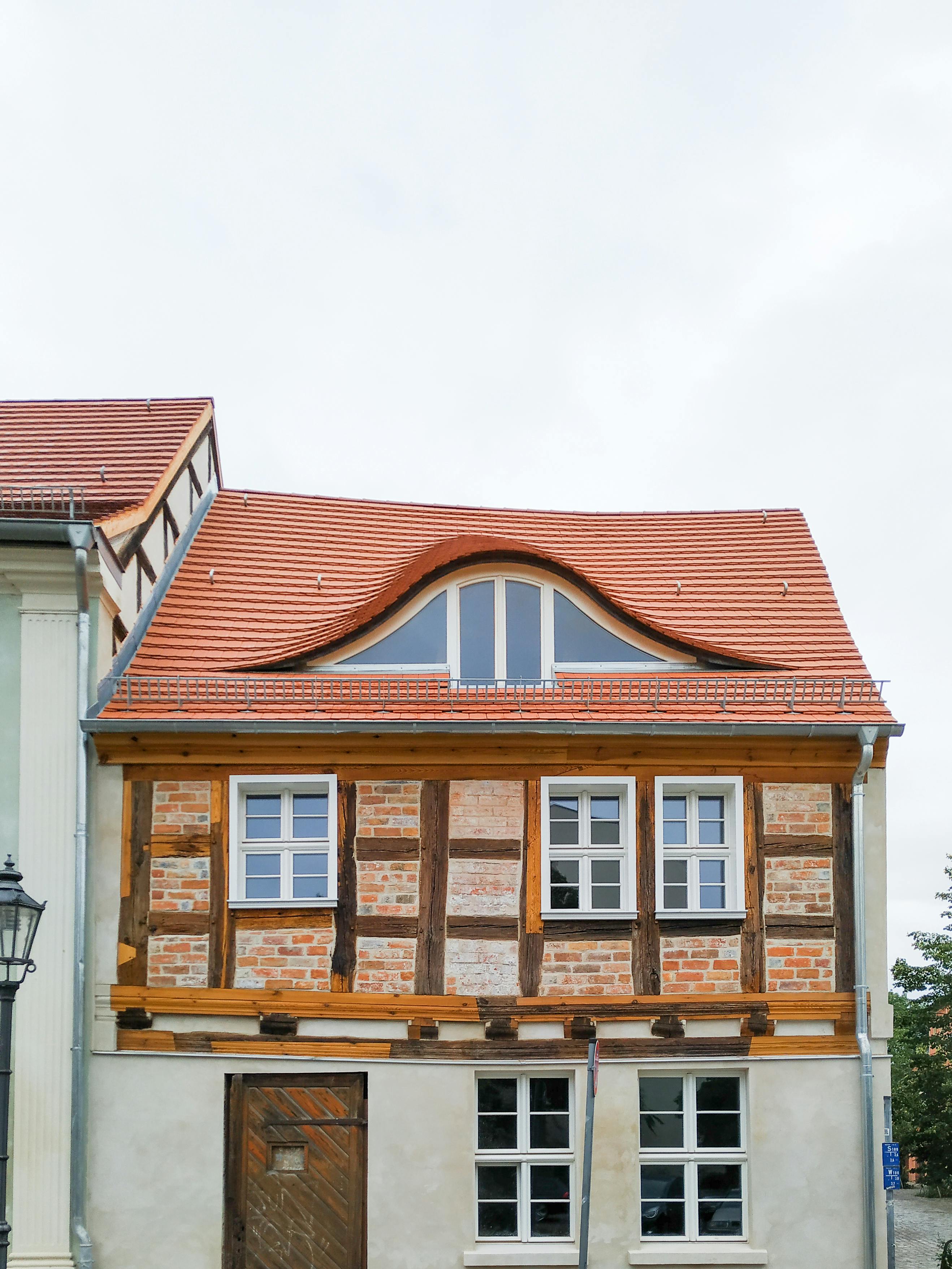 Charming traditional German house in Brandenburg with distinctive curved roof and half-timbered facade.
