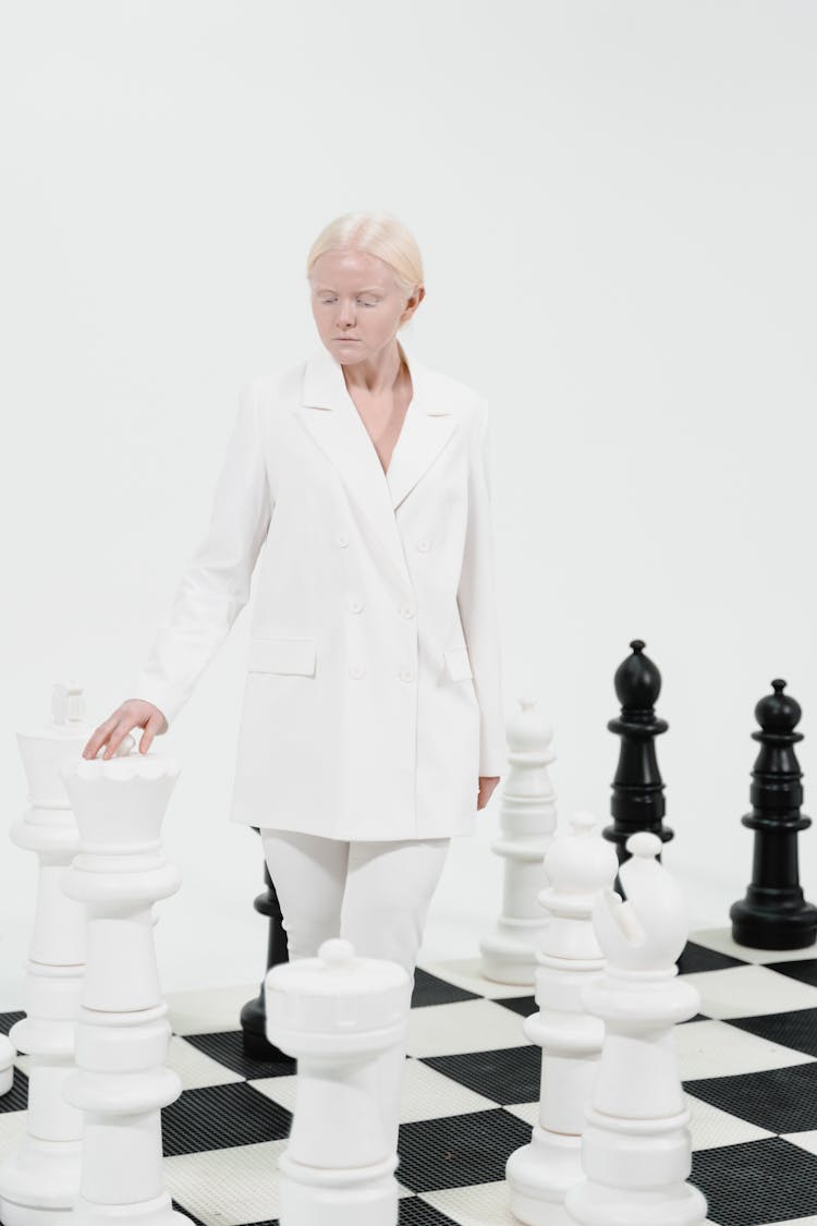 A Woman Walking Besides Giant Chess Pieces