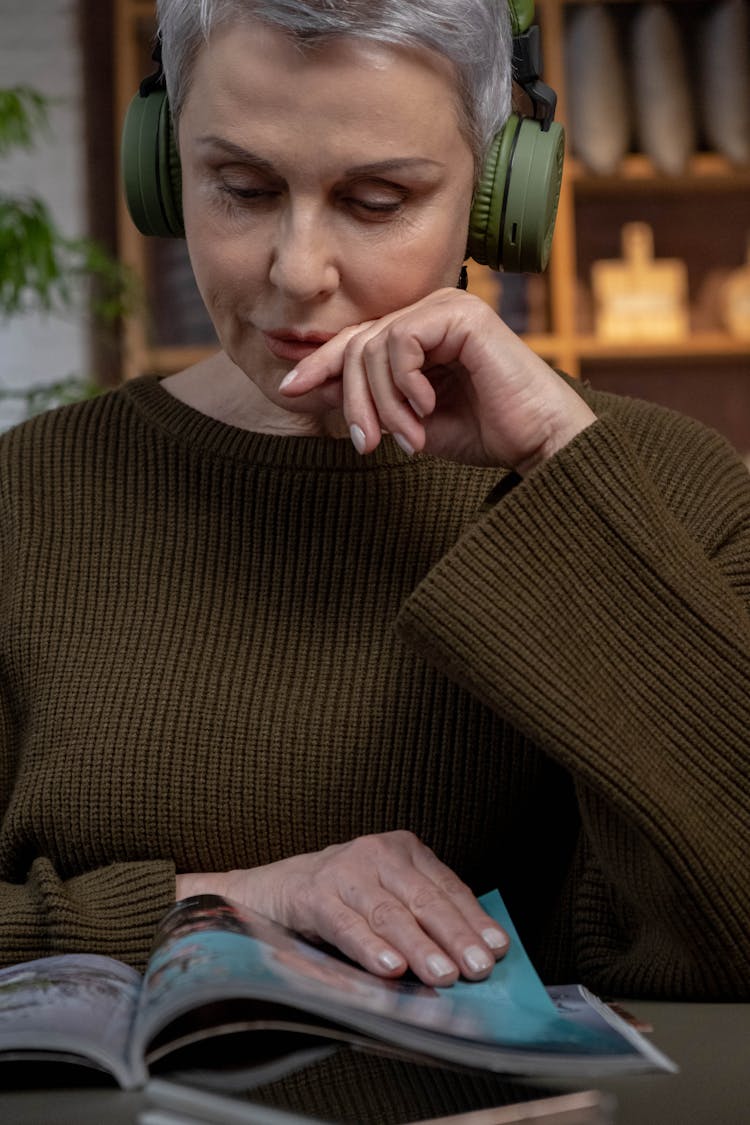 Woman Wearing Headphones Reading A Magazine 