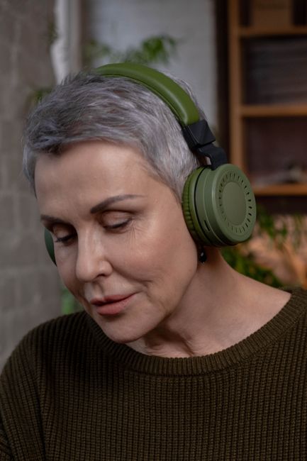 A woman listening with closed eyes and over-ear headphones in a quiet domestic setting, the calm-listening posture for the new-homeowner year.