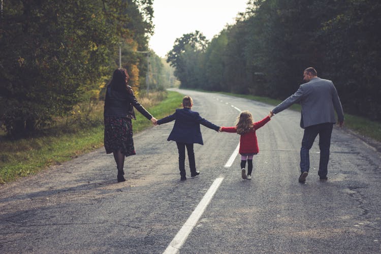 Back View Of A Family Walking On The Road