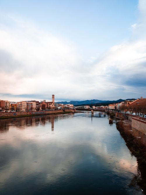 Free Beautiful view of the Tortosa Bridge over the River Ebro with cityscape reflections and cloudy skies. Stock Photo
