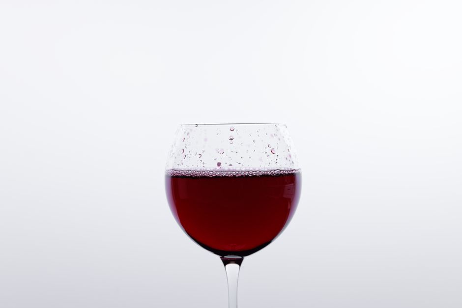 Close-up of a red wine glass on a minimalist white background, ideal for beverage themes.