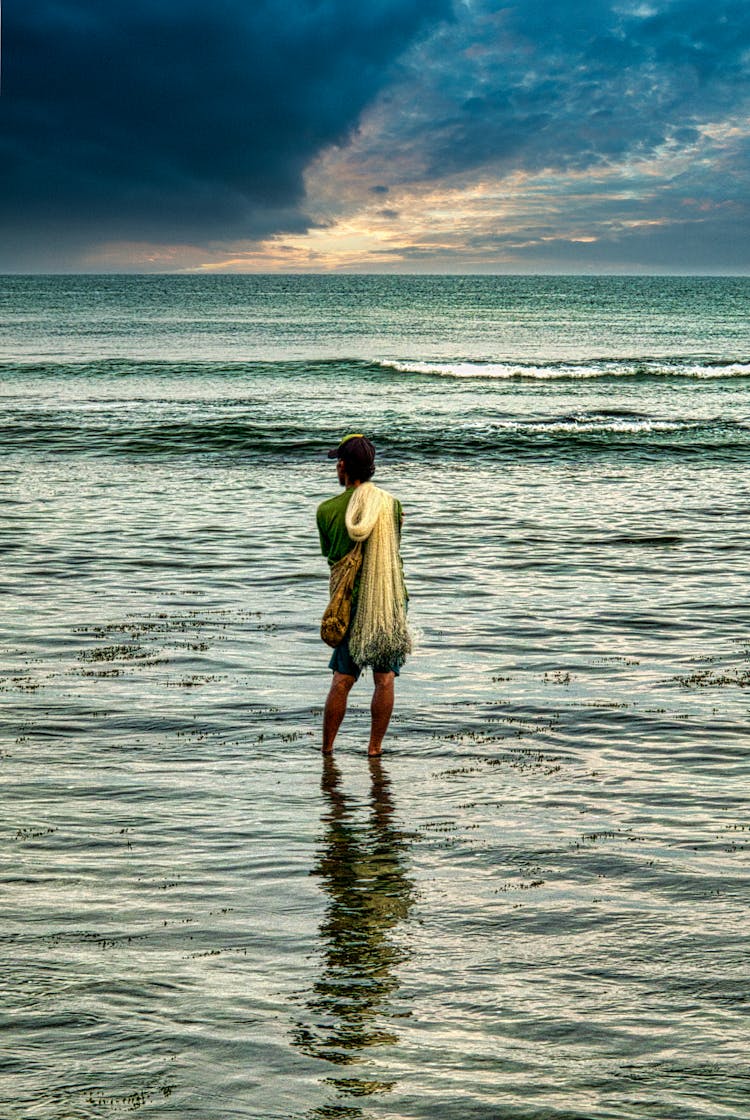 Man Standing Ankle Deep In Sea And Holding A Fishing Net 