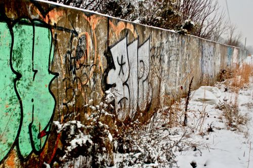 Free Snow-covered graffiti on an urban wall in winter, surrounded by weeds. Stock Photo