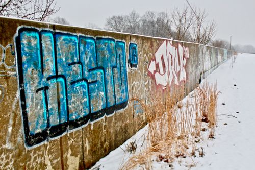 Free Snowy landscape with colorful graffiti on a long concrete wall in winter. Stock Photo
