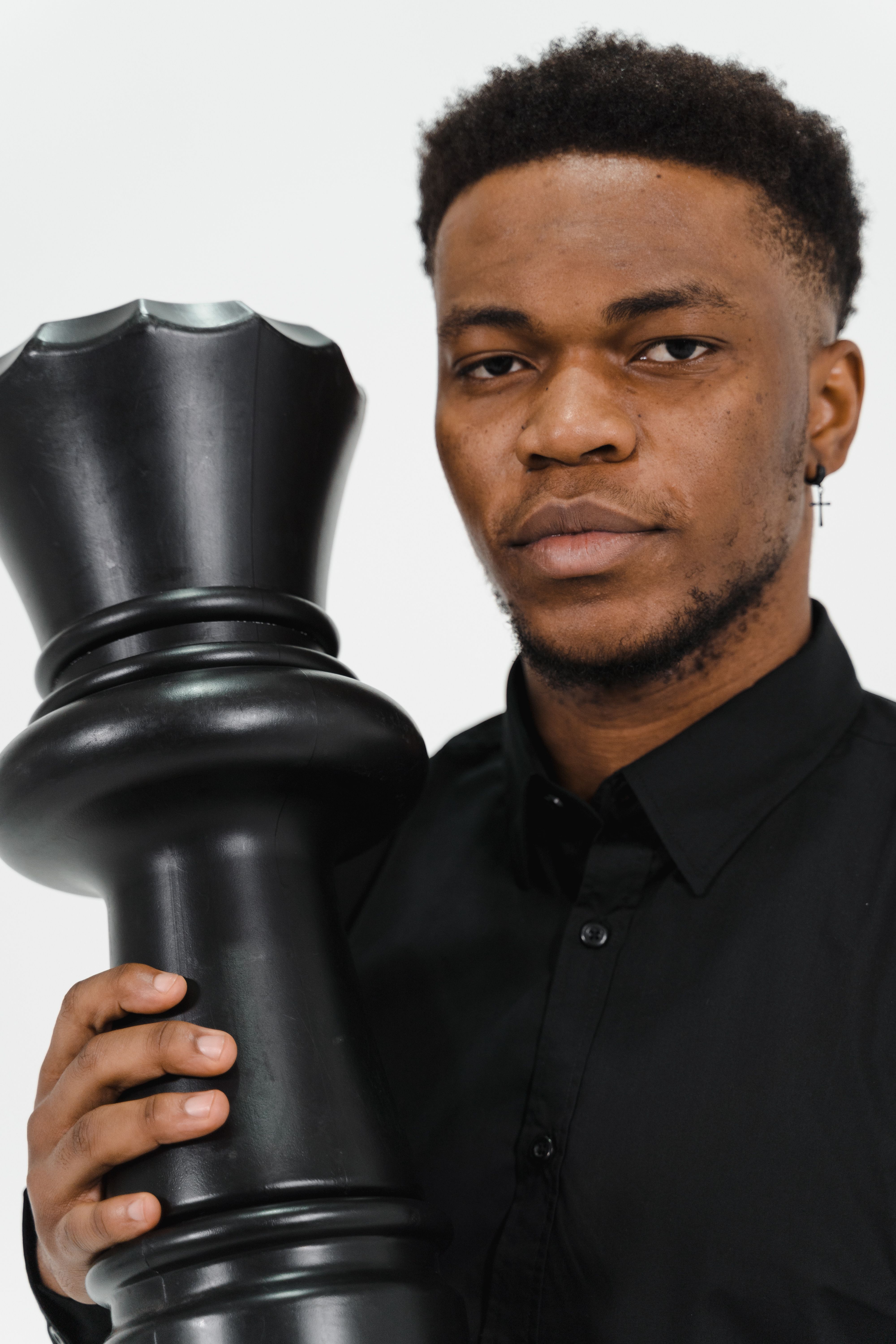 Man with facial hair holding a giant chess piece, symbolizing strategy.