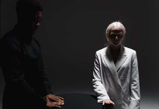 A conceptual studio shot featuring models in contrasting black and white outfits around a round table.
