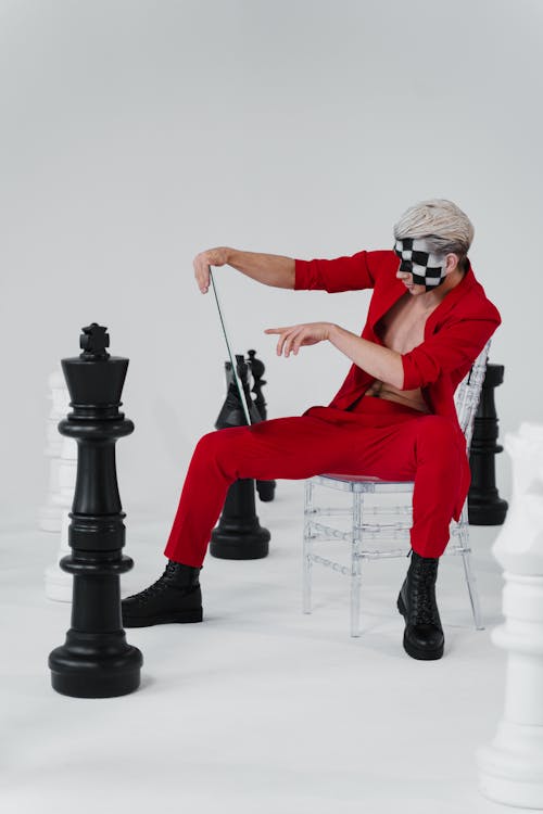 Stylish Man in Red Suit beside Chess Pieces 