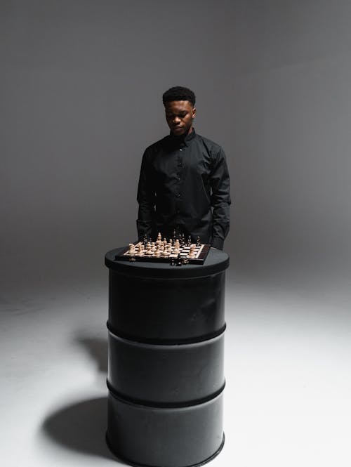 A Man in Black Long Sleeves Standing Beside the Chessboard