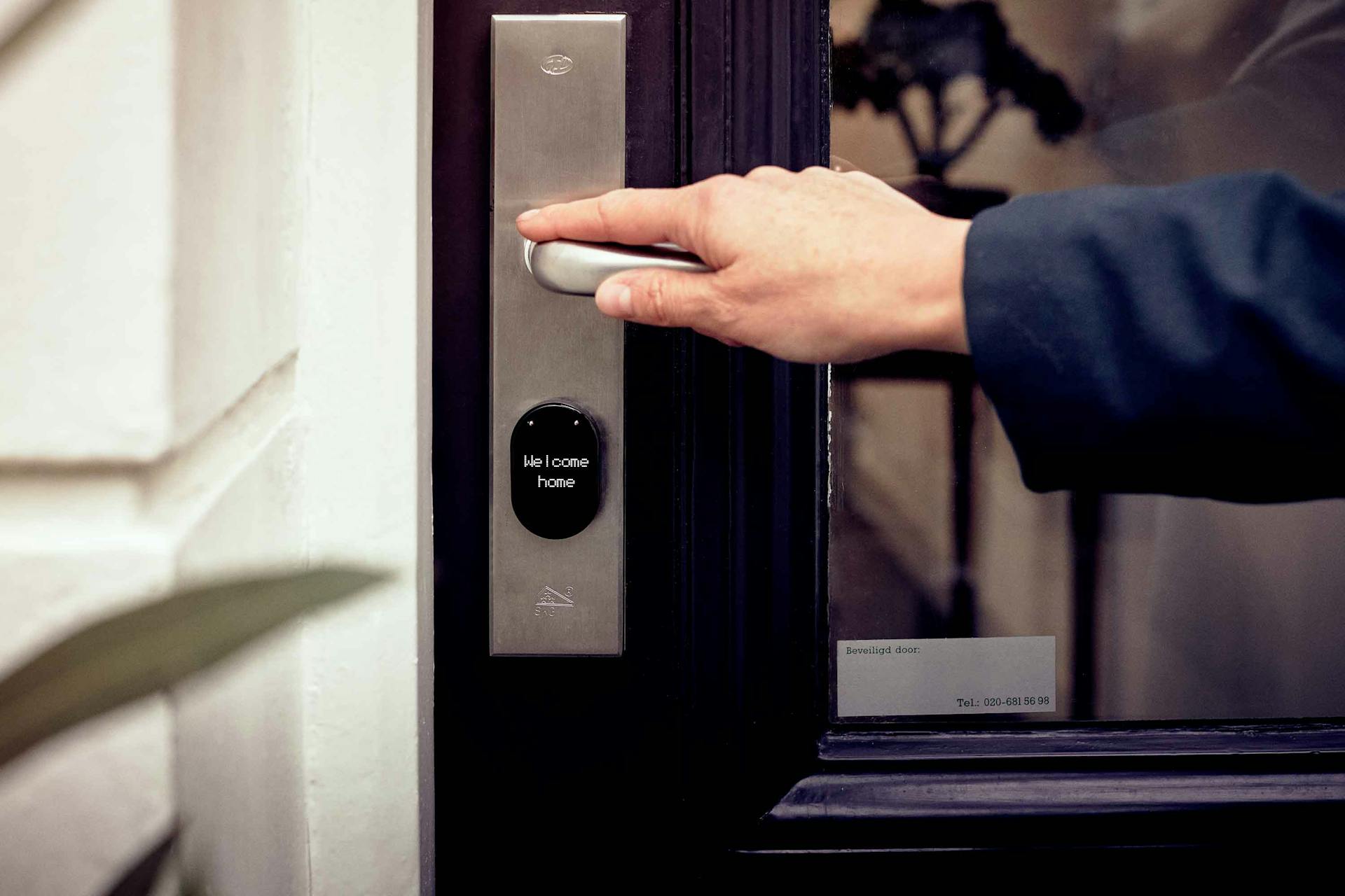 A hand opening a smart home door with digital access panel, conveying security and technology.