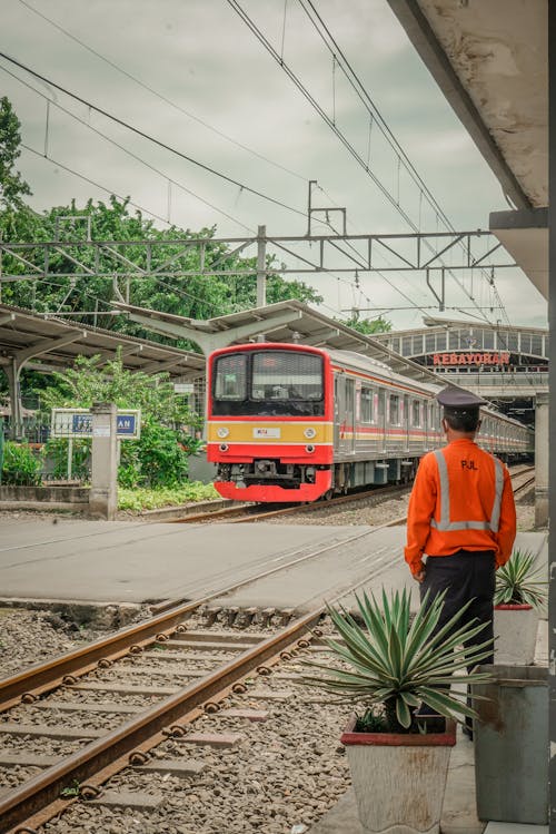 Man in Orange Jacket Standing Near the Railroad