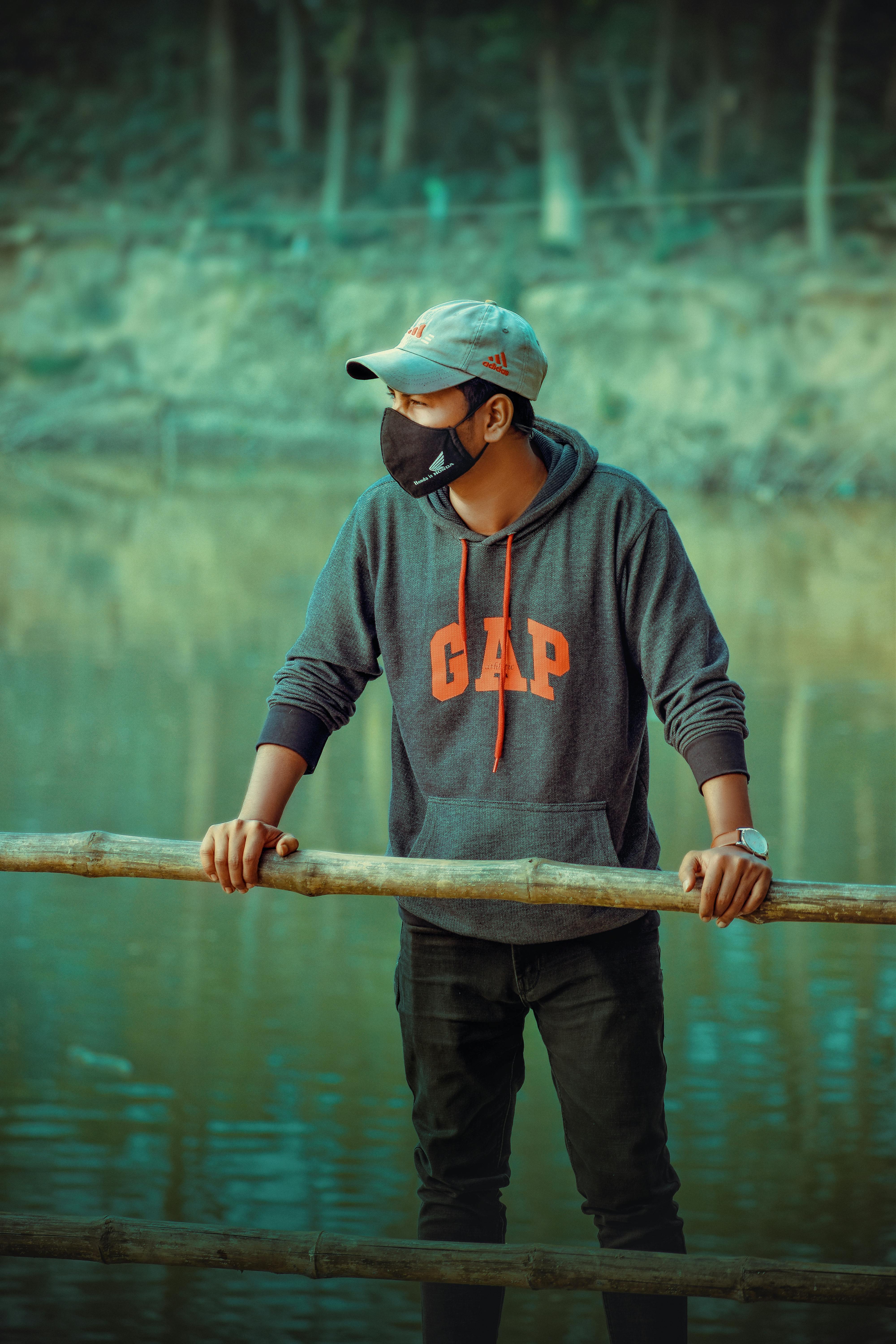 man in black and red hoodie and black pants holding brown wooden stick