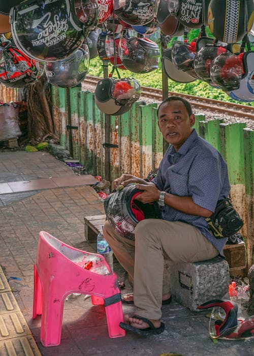 Man in Blue Polo Selling Helmets on Sidewalk