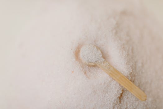 Relaxing still life of a wooden spoon resting in a mound of pink bath salts, ideal for spa and wellness themes.