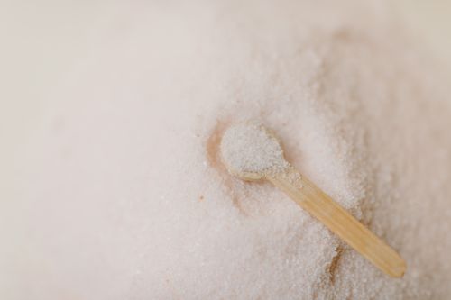 Free Relaxing still life of a wooden spoon resting in a mound of pink bath salts, ideal for spa and wellness themes. Stock Photo
