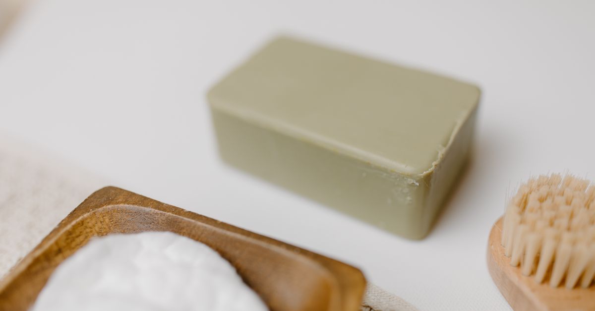 Close-up of a natural soap bar with a wooden brush and cotton pads for skincare.