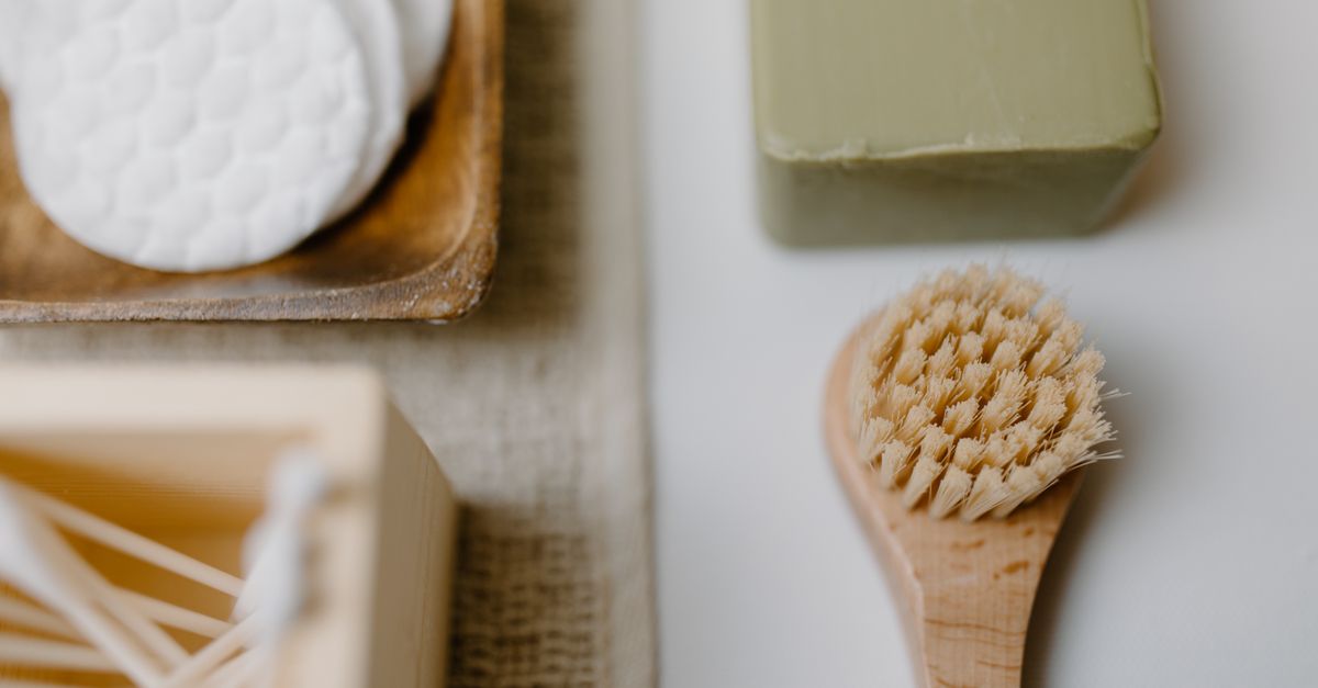 Close-up of eco-friendly bath products including soap and brush on a neutral background.